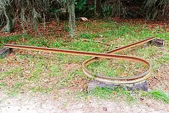 Rusted railroad rail bent in a circle, known as a Sherman's necktie