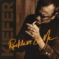 A sepiatone photo of the artist lighting a cigarette in his mouth.