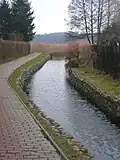 The Niemica River flowing next to a path and under a bridge in Golczewo.