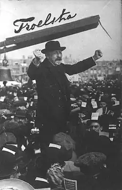 Troelstra stands among a crowd. The name Troelstra is written in handwriting at the top left corner.