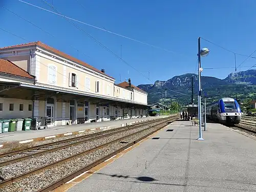 Wide two-story building with hipped roof next to multiple platforms and tracks