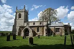 A stone church seen from the south with a battlemented tower to the left and a smaller chancel to the right