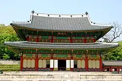 Two storied traditional building with tile roof and walls decorated in red, green and yellow.