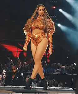 Beyoncé with box braids, wearing an orange glittery top