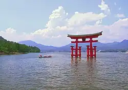 Red and white wooden buildings over water and a large wooden gate in the water