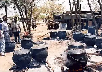دیگ‌های آهنی سه‌پایه که برای پختن غذا در جشن فارغ‌التحصیلی در بوتسوانا استفاده می‌شود.پخت‌وپز روزانه در آشپزخانه مدرسه انجام می‌شود.