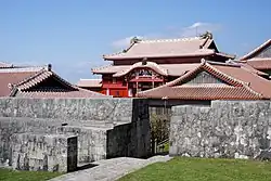 Complex of traditional houses with red tile roofs and a grey wall.