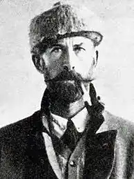 عکس سیاه‌وسفید مردی با کلاه که سیگاری در دهان دارد.