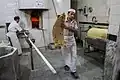 داخل نانوایی یک نفر در حال پختن و دیگری در حال تحویل نان است.