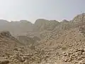 نمای غار شاپور از کنار تابلوی میراث فرهنگی. دور غار یک دایره قرمز کشیده شده‌است.