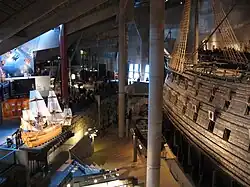 The main hall of the museum with a model of Vasa to the left and the ship itself to the right.