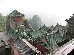 A complex of interconnected traditional houses with tile roofs and red walls.