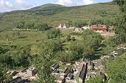 A village in the mountains with a complex of red buildings.