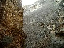 Narrow rocky gorge. A plaque with Chinese text is attached to the rock.