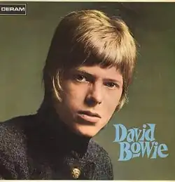 A young man in a mod haircut wearing a high-collared jacket.
